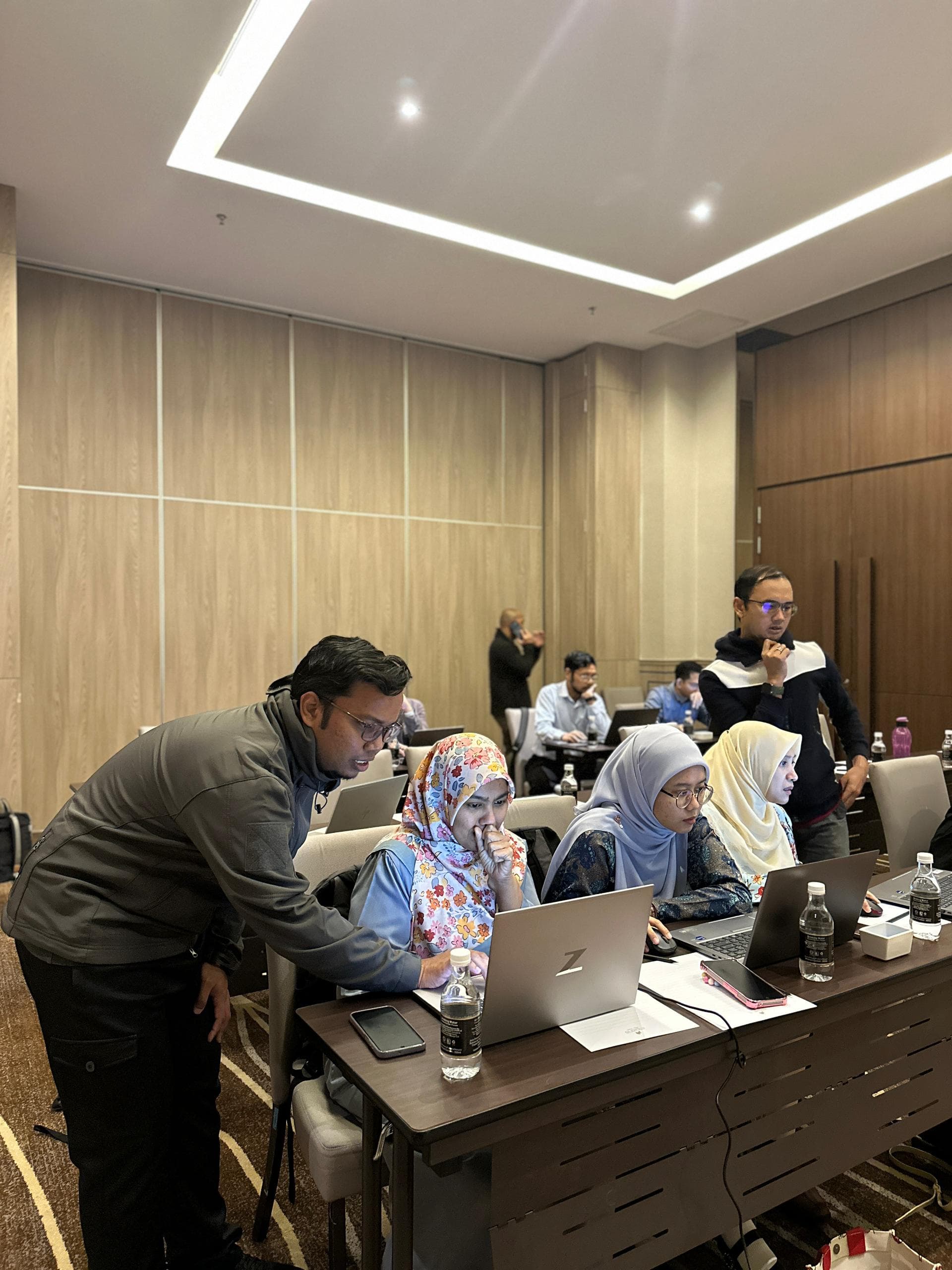 A facilitator helping participants at their laptops during UTM user acceptance testing and training.